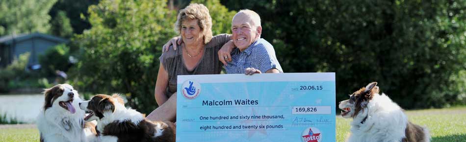 Lotto winner Malcolm Waites with wife Nadine and oversized cheque sitting on their farm